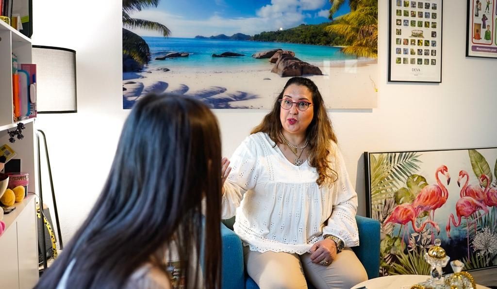 Two women conversing in a room decorated with tropical-themed posters and various colorful items.